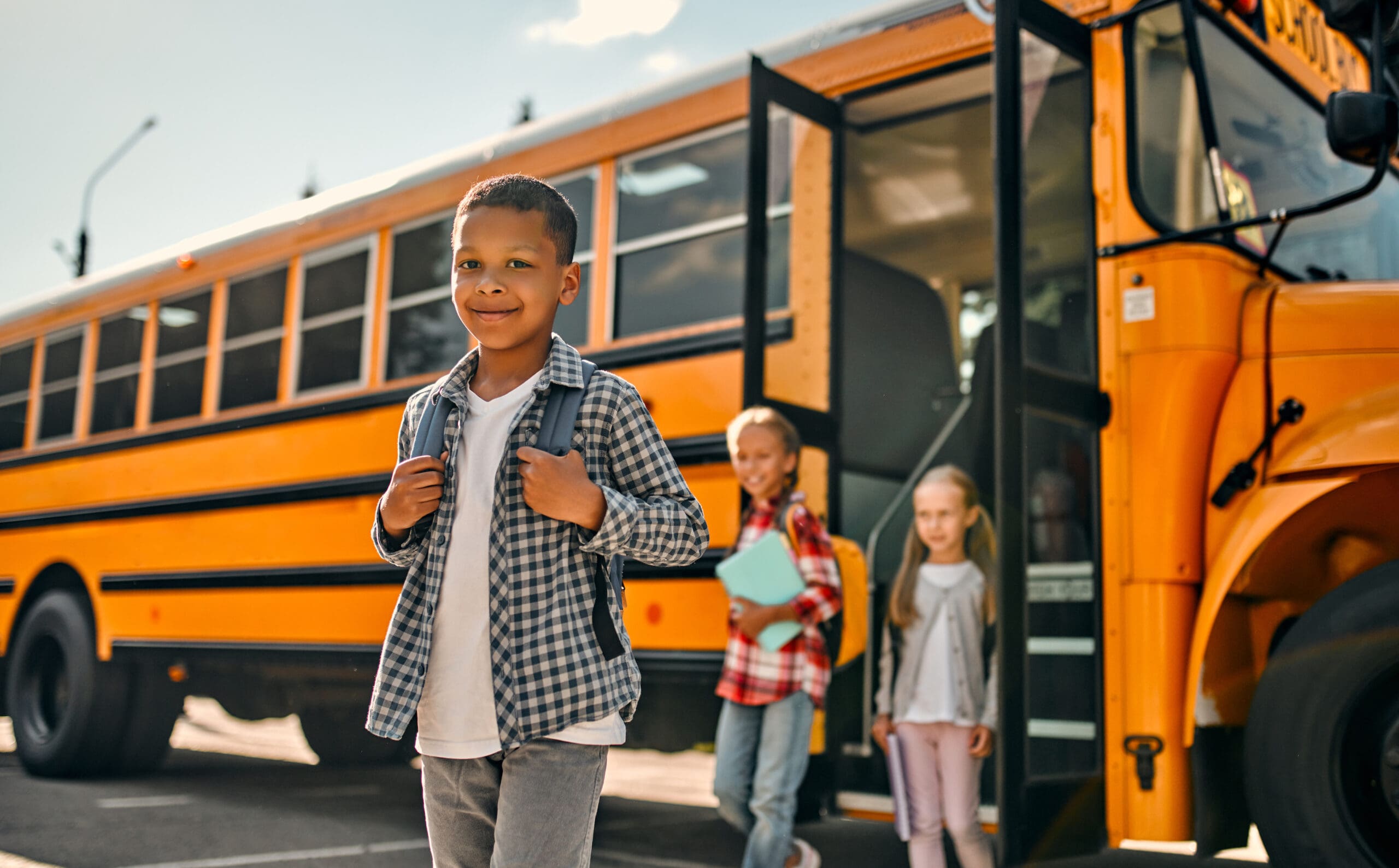 Children walking with a school bus in the background
